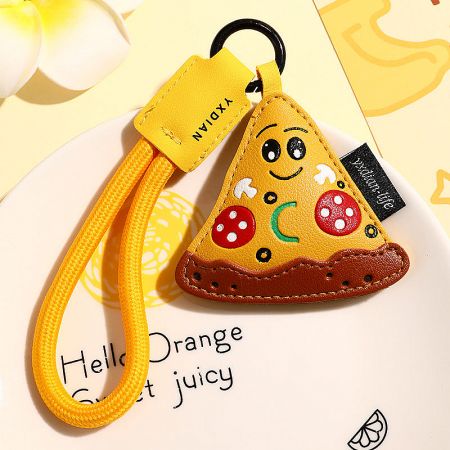 Close-up of the pizza slice PU leather keychain with a cheerful smiling face design.