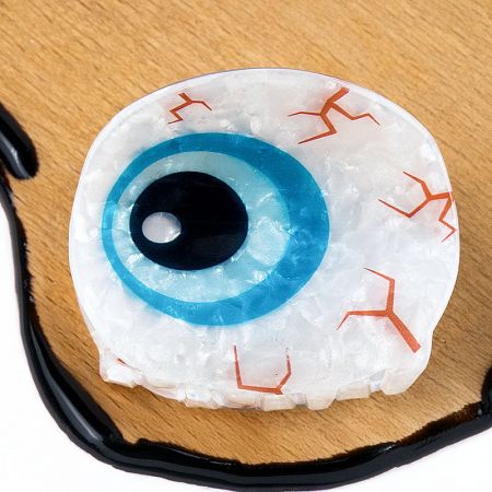 Close-up of a blue Evil Eye hair clip, highlighting the detailed iris design.