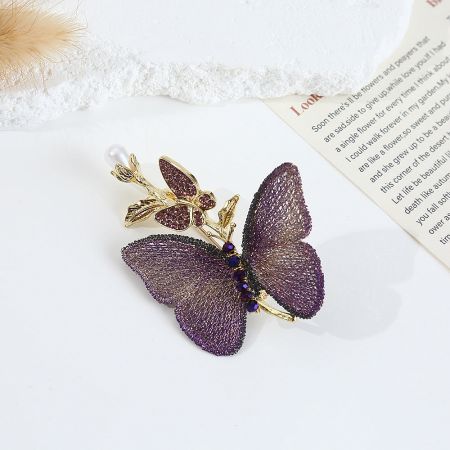 Close-up of the purple embroidered butterfly brooch with faux pearl and gold details.