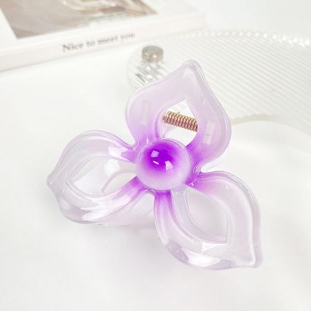 A lovely purple plumeria flower hair clip against a white surface.
