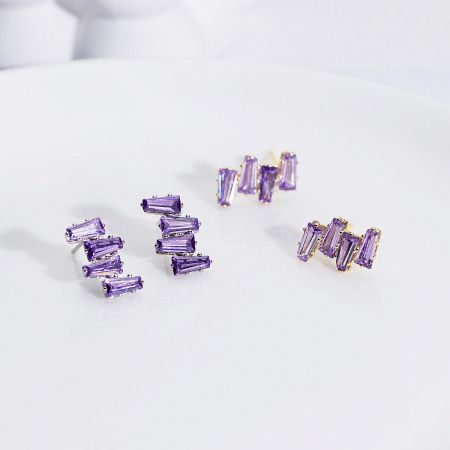 A collection of three pairs of sterling silver stud earrings with purple baguette crystals.