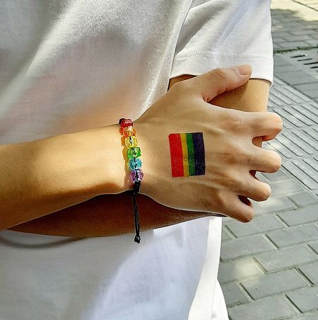 Rainbow Bracelet For Men - A man's wrist wearing the Rainbow Bracelet for Men, featuring vibrant acrylic beads, alongside a matching rainbow temporary tattoo, symbolizing LGBTQ+ pride.