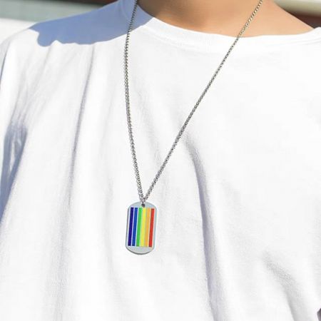 Close-up of a rainbow dog tag pendant from the LGBT Pride necklace collection, worn on a silver chain.