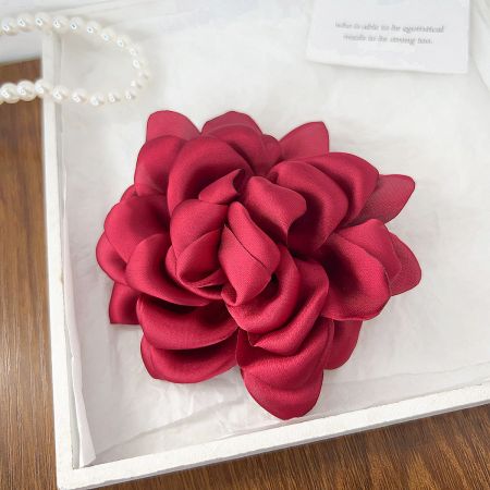 A vibrant red rose fabric flower hair clip, perfect for adding a pop of color.