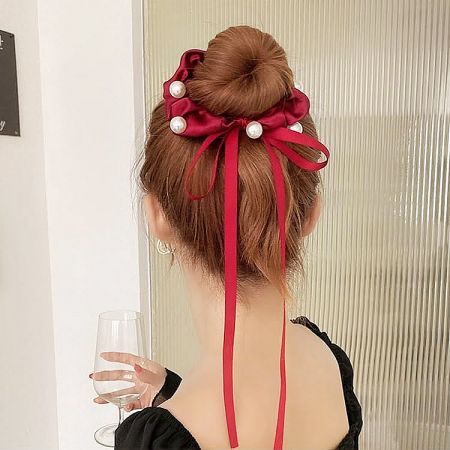 The vibrant red ribbon pearl hair tie styled elegantly in a hair bun.