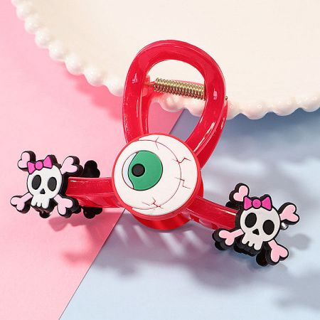 A vibrant red Halloween hair clip featuring a playful eyeball and skull design.
