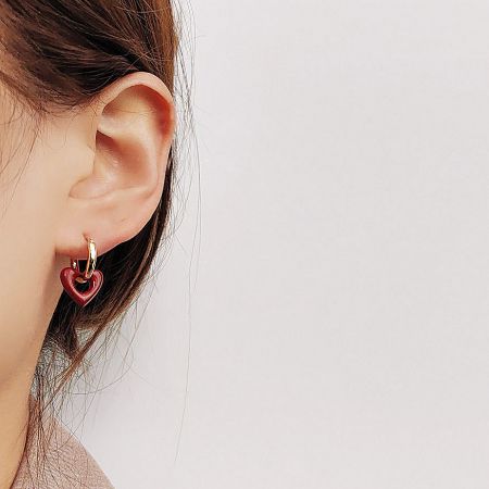 Model wearing the red enamel heart gold hoop earring, showcasing its size and style.