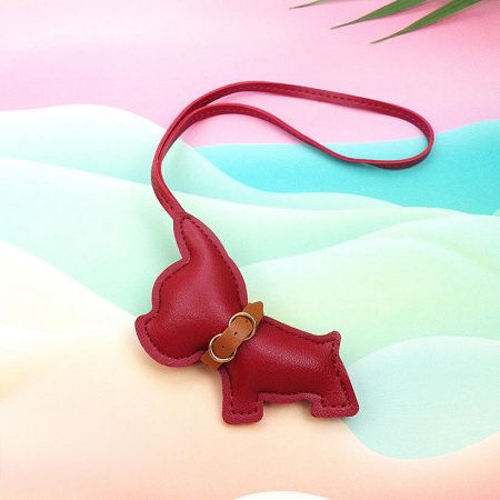 A bold red leather dog-shaped keychain with a strap and buckle detail.