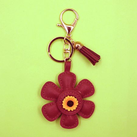 Vibrant red leather sunflower keychain with a yellow center and gold hardware.