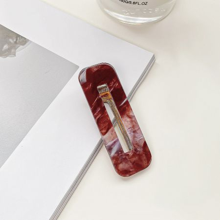 Close-up of a red marbled acrylic hair clip with a geometric square hollow design.