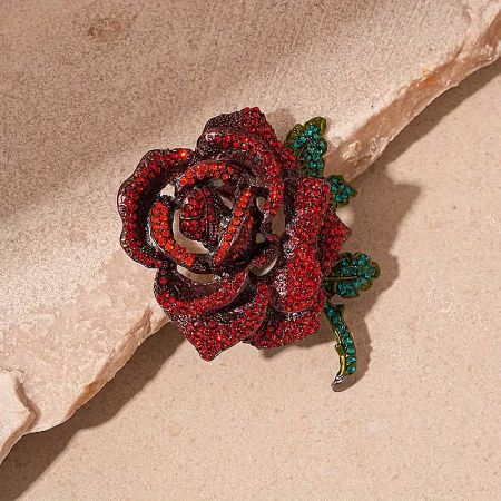 Detailed close-up of the red rose brooch, highlighting the sparkling rhinestones and intricate metalwork.