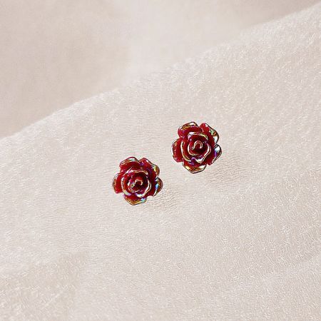 Wholesale Mini 3D Red Resin Rose Flower Stud Earrings (5 Pairs) - A pair of vibrant red, 3D resin rose stud earrings displayed on a neutral textured background, highlighting their detailed craftsmanship.