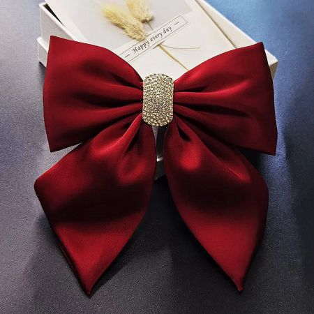 Close-up product shot of the red satin bow hair accessory against a clean white background.