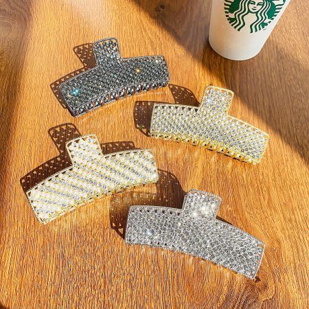 Metal Alloy Crystal Rhinestone Hair Claw Clips (Set of 5) - A set of five large metal alloy hair claw clips, studded with sparkling rhinestones in silver and gold, elegantly arranged on a wooden surface.