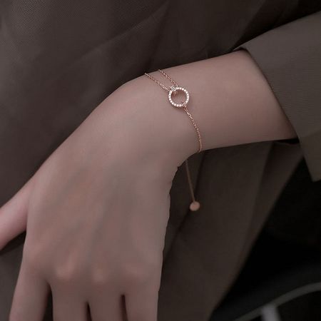 Detailed view of the rose gold bracelet, highlighting the circular charm and brilliant white zircon stones.