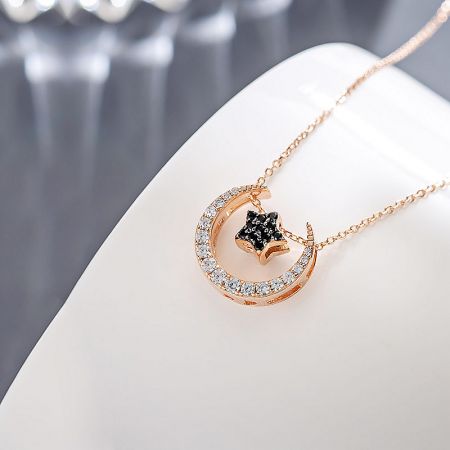 A stylish combination of a rose gold crescent moon pendant with a contrasting black star charm.
