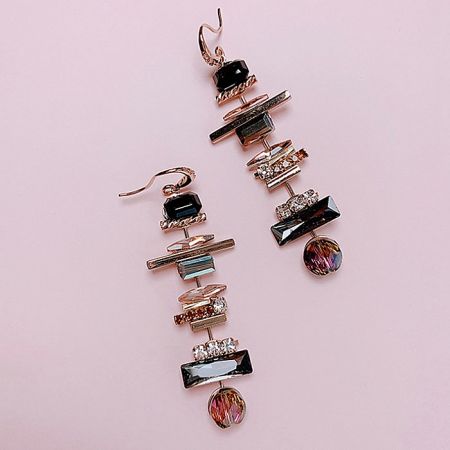 Angled view of the gold dangle earrings highlighting the mix of geometric and round shapes with mixed stones.