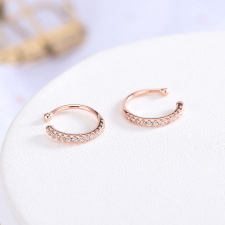 Detailed view of a pair of rose gold ear cuffs with sparkling cubic zirconia.