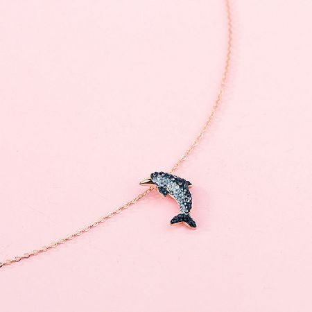 Detailed view of the rose gold dolphin pendant, featuring striking black and white stones.