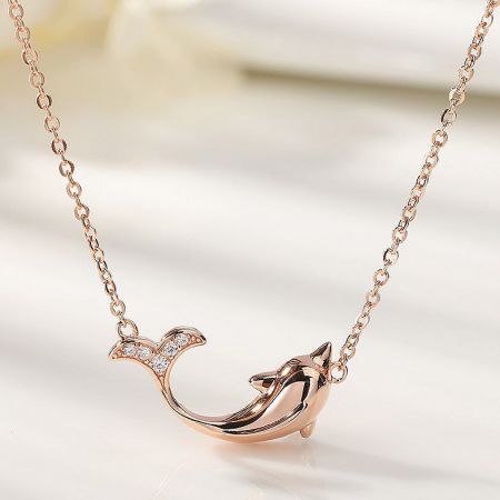 Close-up of the rose gold dolphin pendant with delicate stone accents on the fin.