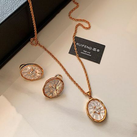 A beautiful rose gold jewelry set with a textured oval pendant necklace and matching earrings, each centered with a diamond.