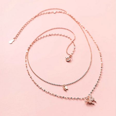 Elegant rose gold layered butterfly necklace with multiple charms.