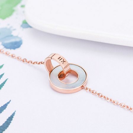 Side view of the rose gold necklace showcasing the circular pendant with white inlay.
