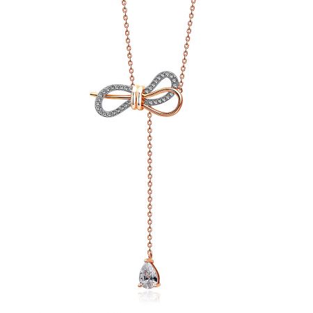 Close-up detail of the intricate diamond-encrusted bow pendant on the rose gold chain.