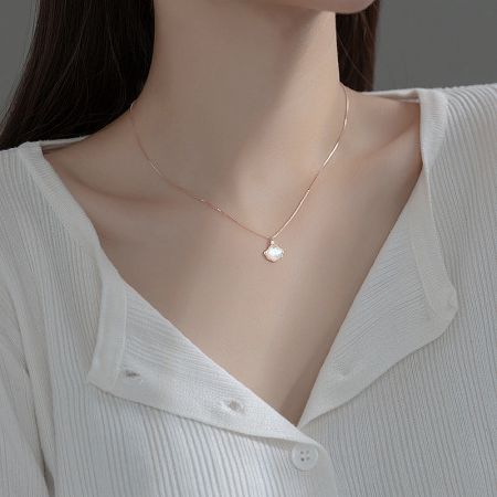 Detailed view of the mother-of-pearl inlay on the rose gold shell pendant.