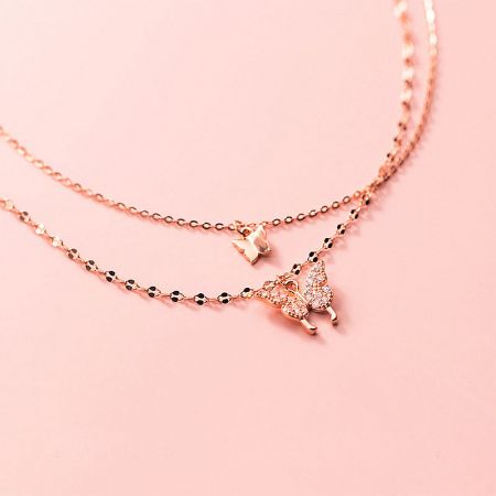 Close-up of two rose gold butterfly necklaces with delicate charms.