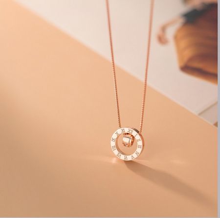 A close-up of the rose gold rotating pendant necklace, showcasing the intricate Roman numeral details.