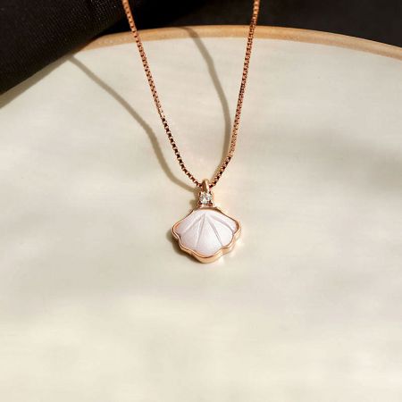 Angled shot of the sterling silver seashell necklace in a rose gold finish.