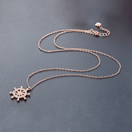 Elegant rose gold ship's wheel pendant necklace, showcasing its warm tone and brilliant stone embellishments.