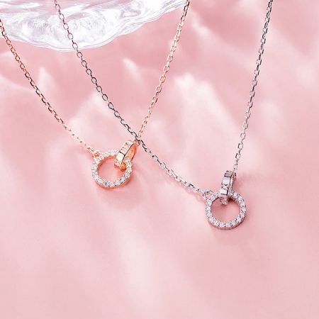 The complete set of interlocking circle pendant necklaces in silver and rose gold, presented together.