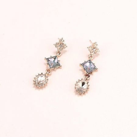 Close-up of the geometric dangle earrings with star and round gemstones.