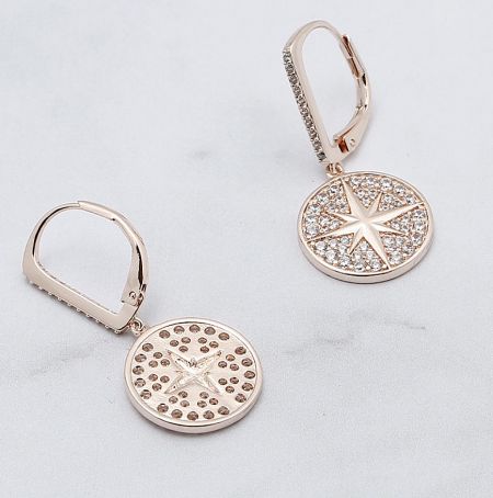 A pair of Sunburst Drop Earrings laid flat on a white surface, showcasing the detailed craftsmanship and sparkling stones.