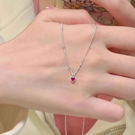 Hand holding the sterling silver necklace with a ruby heart zircon pendant.