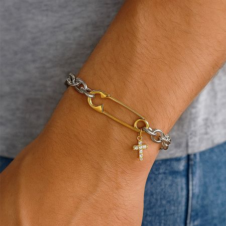 Detailed close-up of the zircon-studded cross charm and safety pin link on the stainless steel bracelet.