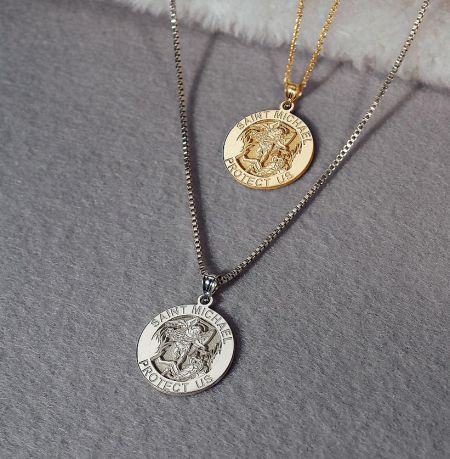 Gold and silver variations of the Saint Michael Protect Us pendant.