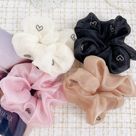 An assortment of four scrunchies in pink, white, black, and brown, perfect for matching any outfit.