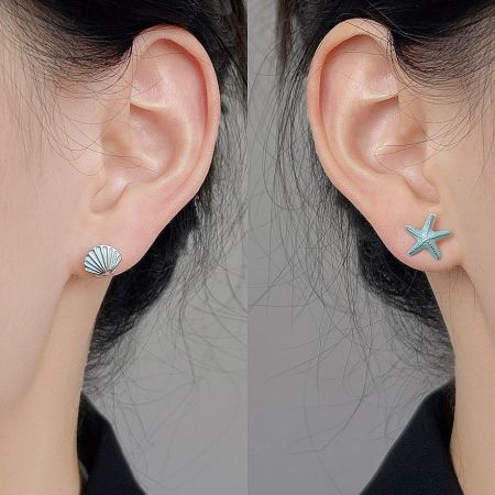 Model wearing the asymmetrical starfish and seashell stud earrings.
