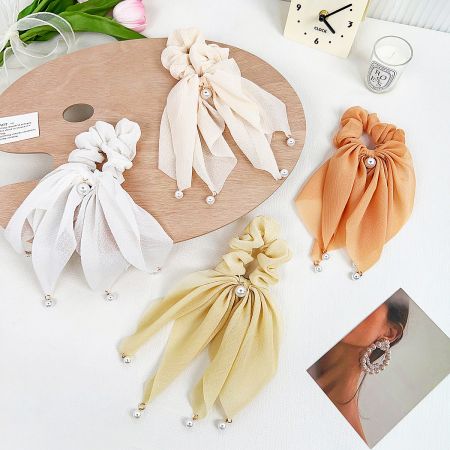 A collection of silk scrunchies with pearl embellishments in various colors.