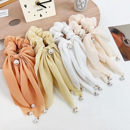 A set of silk scrunchies with pearl embellishments in different pastel colors.