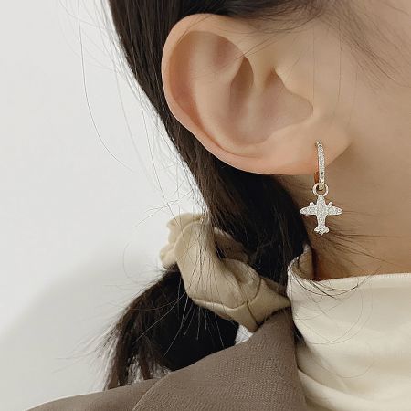 Model wearing the airplane charm earring, demonstrating its size and fashionable look.