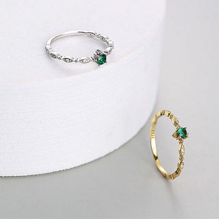 Top-down view of the silver and gold rings with brilliant green gemstones.