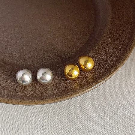 Top-down view of the gold and silver plated brass stud earrings on a decorative plate.