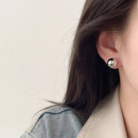 Close-up of a woman wearing the silver 12mm ball stud earring, highlighting its classic style.