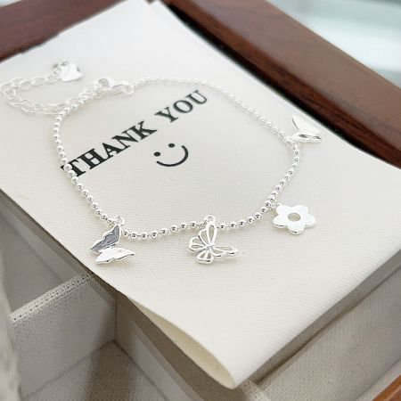 A sterling silver charm bracelet displayed on a thank you card, highlighting its quality for gifting.