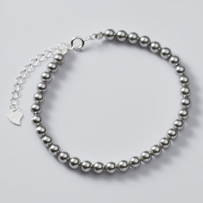 Detailed view of the silver pearl bracelet featuring a delicate heart charm.