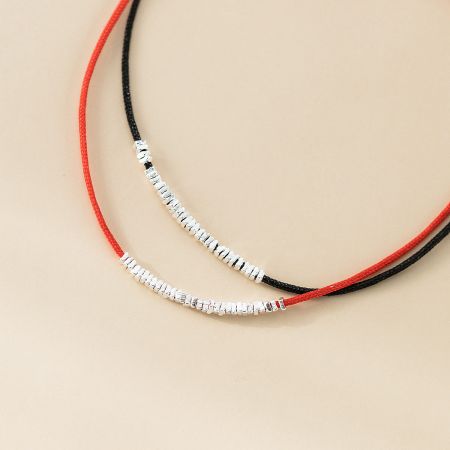 Detailed view of the red and black cord bracelets, showing the quality of the sterling silver beads.